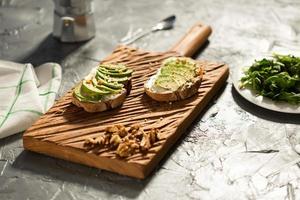 Sliced avocado on toast bread with nuts. Breakfast and healthy food concept. photo