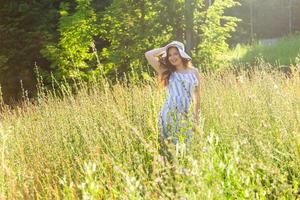 mujer joven caminando entre flores silvestres en un día soleado de verano. concepto de la alegría de comunicarse con la naturaleza de verano foto