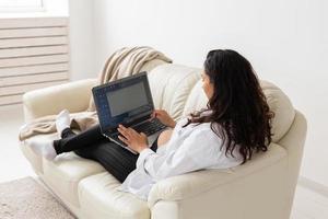 Pregnant woman using laptop while sitting on a couch in the living room at home photo