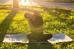 Pregnant woman doing yoga in nature outdoors. Healthy lifestyle, expecting baby and childbearing concept. photo