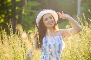 mujer joven caminando entre flores silvestres en un día soleado de verano. concepto de la alegría de comunicarse con la naturaleza de verano foto