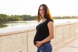 mujer hispana embarazada en el parque, tocando el vientre foto