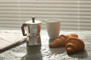 Breakfast with croissant and coffee and moka pot. Morning meal and breakfast concept. photo