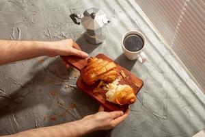 desayuno con croissant en tabla de cortar y café negro. concepto de comida y desayuno por la mañana. foto