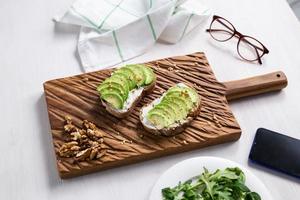 Sliced avocado on toast bread with nuts. Breakfast and healthy food concept. photo