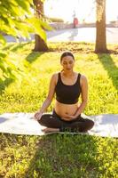 Young pregnant woman meditating in nature, practice yoga. Care of health and pregnancy photo