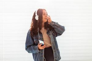 Beautiful young peaceful pregnant woman listens to pleasant classical music using smartphone and headphones. Concept of positive attitude before childbirth. Copy space photo