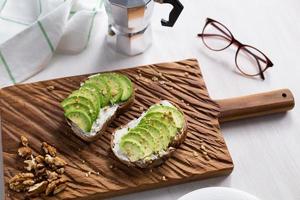 Sliced avocado on toast bread with nuts. Breakfast and healthy food concept. photo