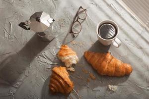 desayuno con croissant en tabla de cortar y café negro. concepto de comida y desayuno por la mañana. vista superior. foto