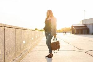 Active pregnancy concept. Young pregnant business woman or student sitting on the bench. Future mom working or studying on her late pregnancy period. photo