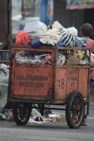Magelang,Indonesia,2023-Garbage people working together emptying dustbin to dispose of trash with truck loading garbage and dustbin. photo