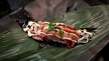 Piece of Burned Wagyu or Australia beef sushi with mayonnaise on bamboo leaf on black dish or plate at Japanese restaurant. Delicious Asian food, tasty and diet, healthy meal life style eating. photo