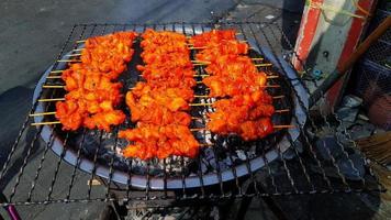 Grilled red chicken, beef or pork charcoal stove on local street food in Thailand. Barbeque in Thai style. Cooking Asian food. Delicious meal and taste sweet with ingredient and spices or pimento. photo