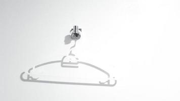 White plastic clothes hanger hanging on white wall with copy space. Object for clothing. photo