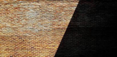 Brown or red brick wall with shadow for background. Art and Pattern wallpaper. Rough and Grunge exterior or interior design with copy space photo