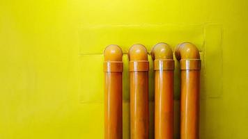 cuatro tuberías de agua amarillas en un muro de hormigón amarillo para fondo con espacio de copia. tubería de aceite instalada en el piso. foto