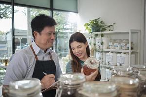 dos colegas comerciantes verifican el stock de productos orgánicos naturales en estantes de contenedores reutilizables en la tienda de recarga, cero desperdicio, tienda de comestibles sin plástico y estilos de vida ecológicos y sostenibles. foto