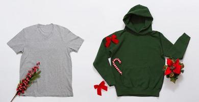 primer plano banner verde plantilla en blanco sudadera con capucha conjunto de camiseta espacio de copia. concepto de vacaciones de navidad. sudadera con capucha de maqueta de vista superior. decoraciones navideñas rojas sobre fondo blanco de puente. feliz año nuevo accesorios. foto