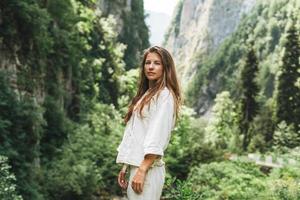 Young woman traveler with long blonde hair looks at the beautiful view of mountains photo