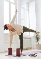 Attractive middle aged brunette woman in sportswear ptactice yoga with equipment in the light studio photo