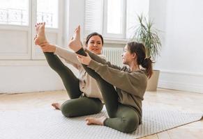 Attractive mother middle age woman and daughter teenager ptactice yoga together in the bright room photo