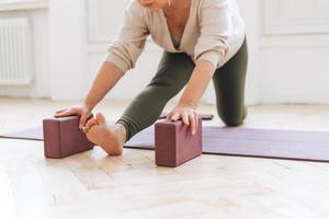 Attractive middle aged brunette woman in sportswear ptactice yoga with equipment in light studio photo