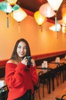 Beautiful smiling young asian woman in red with cup of tea in the chinese restaurant photo