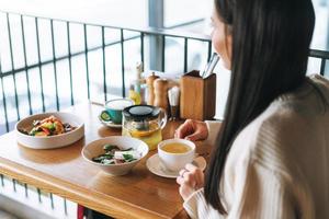 Attractive young brunette smiling woman in casual having brunch in the cafe, healthy food photo