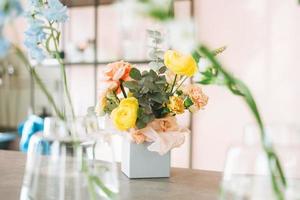 Flower arrangement with yellow and pink roses and eucalyptus in gift box on table in flower shop, modern floristic photo