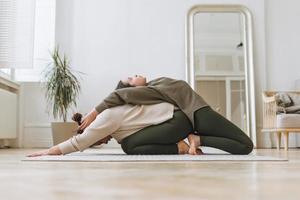 madre atractiva mujer de mediana edad e hija adolescente practican yoga juntas en una habitación luminosa foto