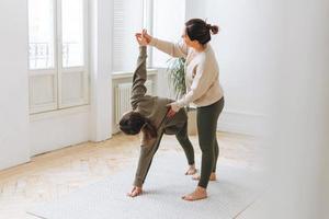 Attractive mother middle age woman and daughter teenager ptactice yoga together in bright room photo