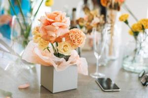 Flower arrangement with yellow and pink roses in gift box on table in flower shop, modern floristic working place photo
