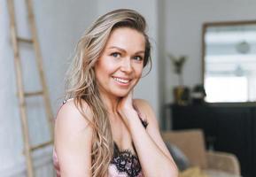 retrato de belleza de una mujer rubia sonriente de 35 años limpiando la cara y las manos frescas con el pelo largo en un baño ligero foto