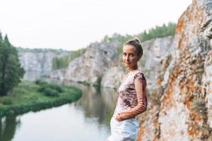 Portrait of Young slim woman looks at the beautiful view of the mountains and the calm river, local travel photo