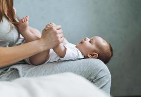 joven madre divirtiéndose con una linda niña de rodillas sentada en la cama en casa, ama la emoción foto