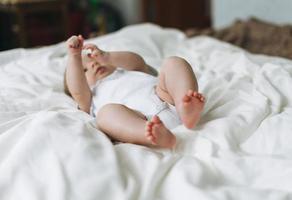 Cute baby girl 2-4 month on bed with white linen, natural tones, selective focus photo