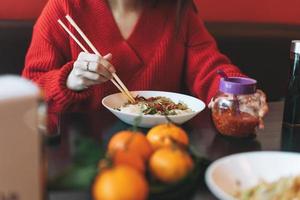 bella joven asiática sonriente vestida de rojo comiendo comida asiática en un restaurante vietnamita chino foto