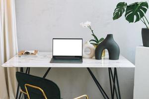 Modern workplace with an open laptop with white screen and green monstera on marble table, mock up, template photo