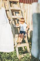 Cute blonde climbs up the ladder countryside cottagecor on the summer photo