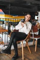 Brunette smiling young woman photographer working with her camera in the cafe photo