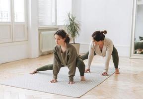 Attractive mother middle age woman and daughter teenager ptactice yoga together in the bright room photo