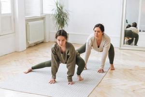 Attractive mother middle age woman and daughter teenager ptactice yoga together in bright room photo