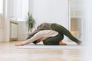 madre atractiva mujer de mediana edad e hija adolescente practican yoga juntos en la habitación luminosa foto