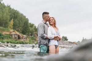 Happy young couple in love travelers kissing in the mountain river photo