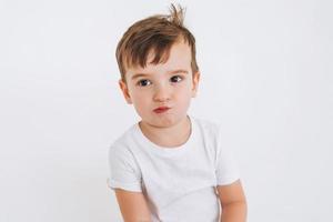 Funny cute thoughtful toddler boy in white t-shirt on the white background photo