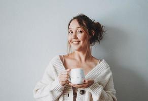 Attractive friendly smiling brunette woman middle age with cup of cocoa with marshmallow at home photo