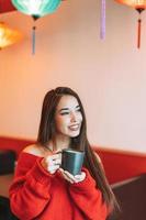 Beautiful smiling young asian woman in red with cup of tea in the chinese restaurant photo