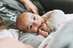 familia real de mamá joven y dos niños de diferentes edades, una adolescente y un bebé divirtiéndose en la cama foto