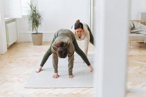 Attractive mother middle age woman and daughter teenager ptactice yoga together in bright room photo