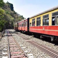 Shimla, Himachal Pradesh, India - May 14, 2022 - Toy train Kalka-Shimla route, moving on railway to the hill, Toy train from Kalka to Shimla in India among green natural forest photo